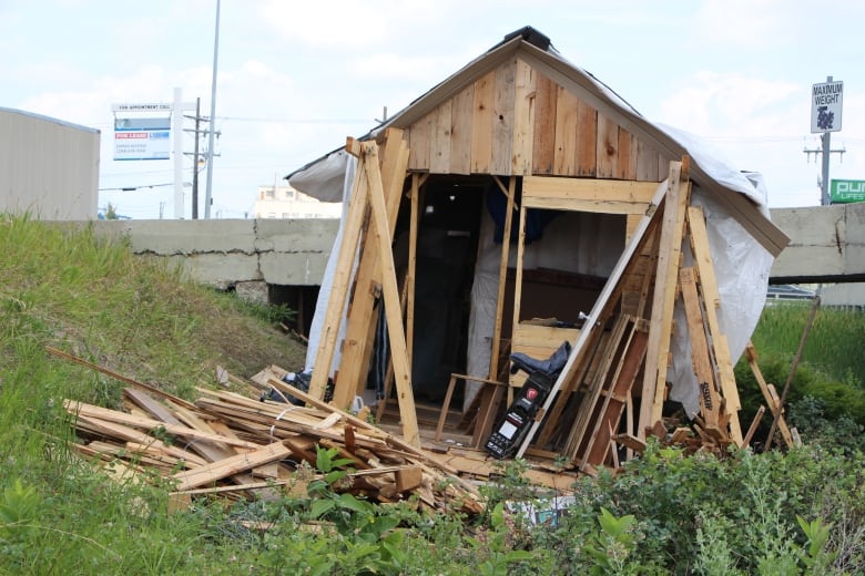 Pieces of wood sit around a slanting wooden shack.