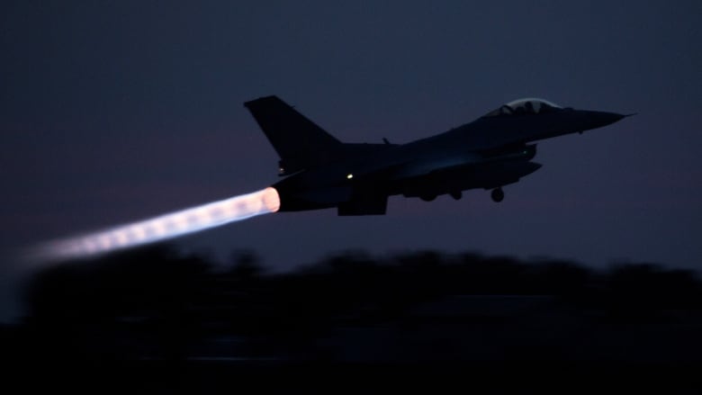 A fighter jet takes off in darkness.