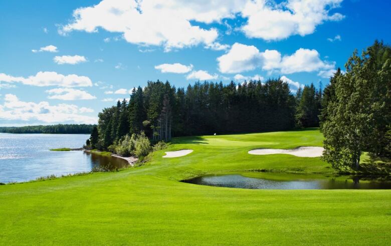 Bright blue skies over a brilliant green golf course by the side of the ocean.