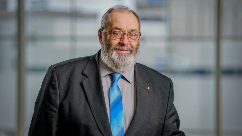 A smiling man with a large beard wearing a suit