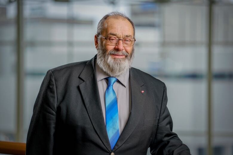 A smiling man with a large beard wearing a suit