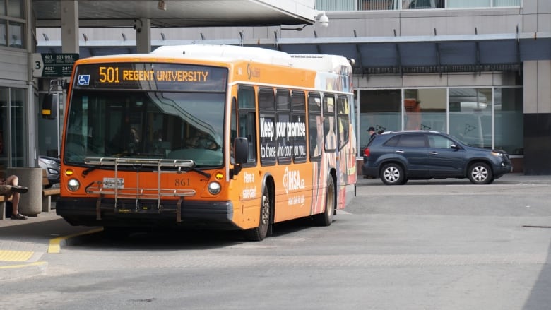 An orange city bus at a transit terminal.