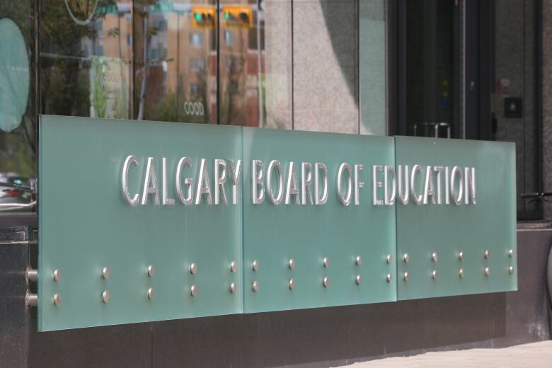 A frosted glass sign sits outside a building. The sign reads: Calgary Board of Education.