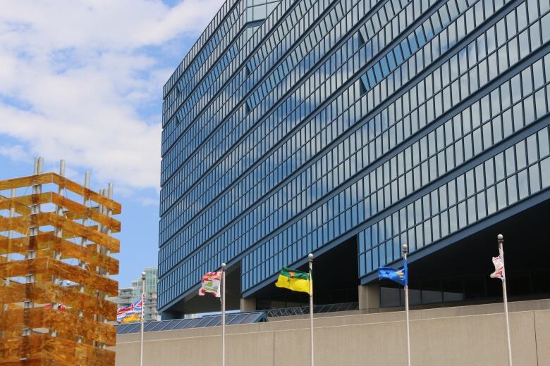 a glass building with many windows. various flags stand in front, blowing in the wind.