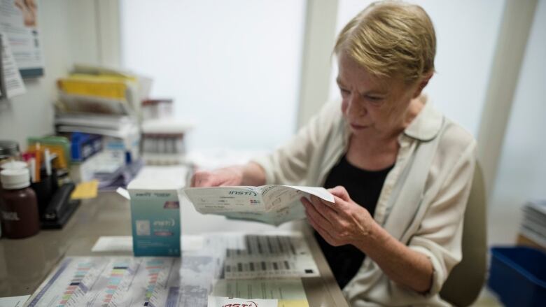 A woman sits at a desk and reads through an information packet