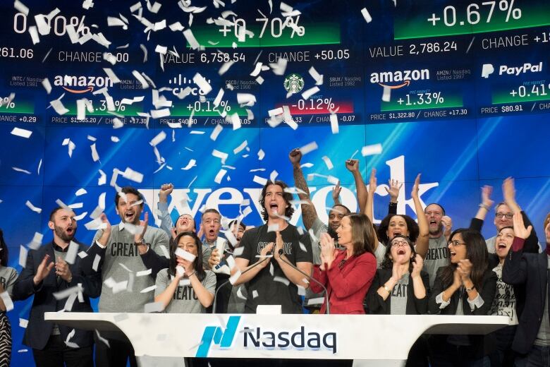 Adam Neumann, center, co-founder and CEO of WeWork, attends the opening bell ceremony at Nasdaq