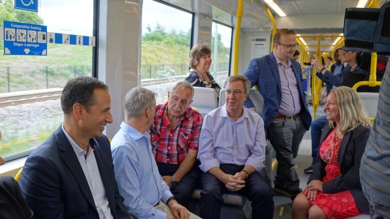 Several people sit and talk while riding inside a train