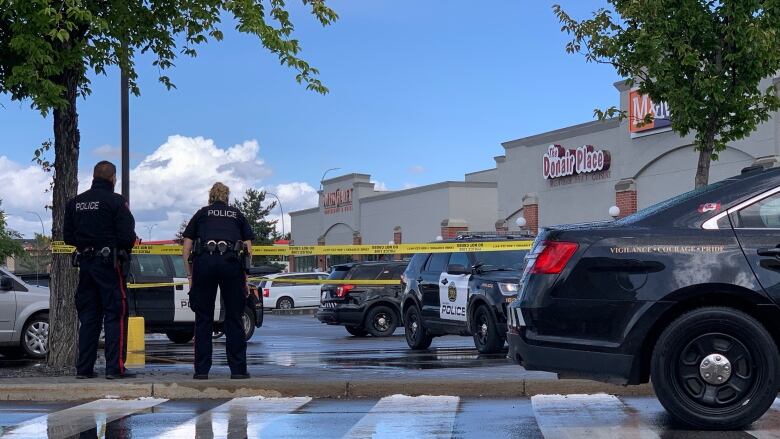 Two police officers and two police vehicles are outside a shopping mall.