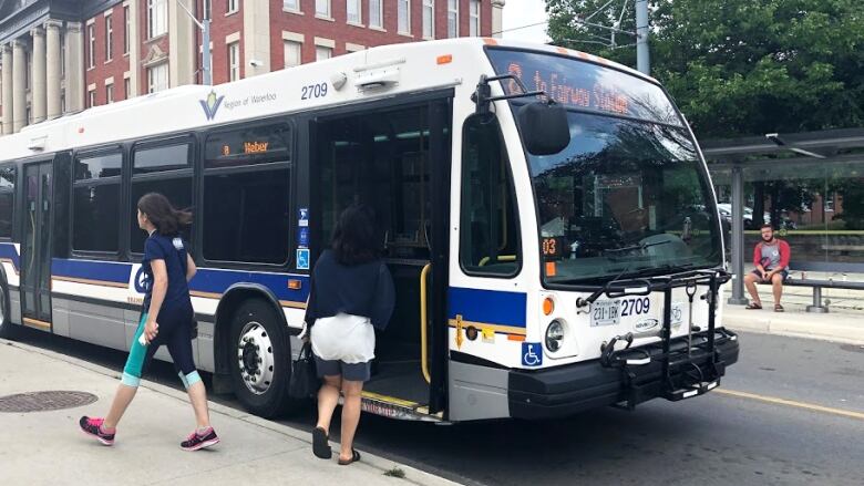 People getting off and boarding a public transit bus.