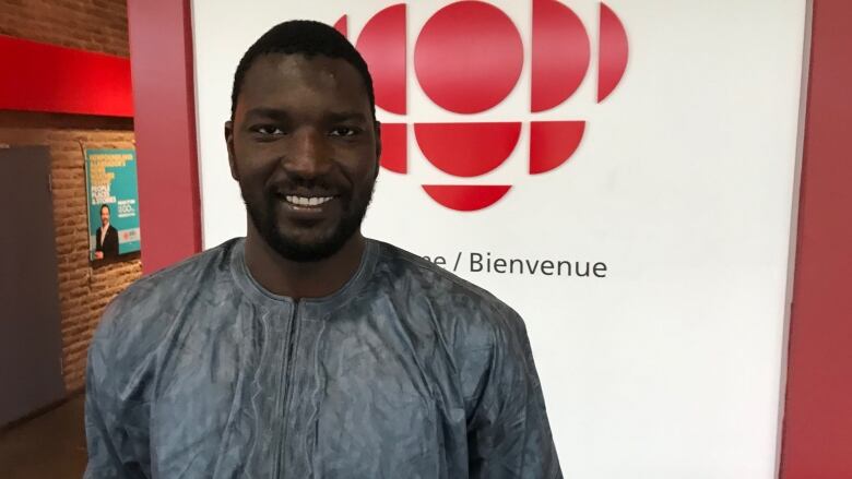 An African-Canadian man smiles to the camera. 