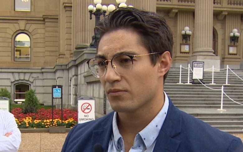 The head of the  Canadian Taxpayers Federation stands on the grass in front of a building.