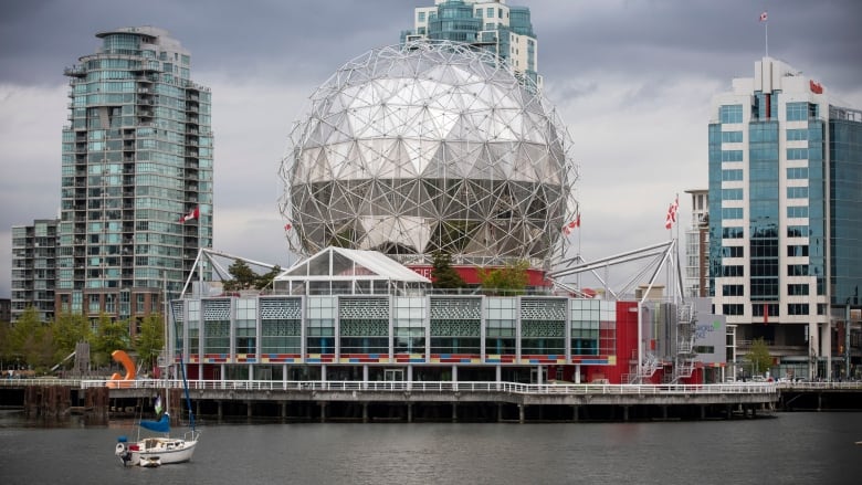 An exterior shot of Science World shows a geodesic dome structure nestled between condo buildings along the waterfront in Vancouver.