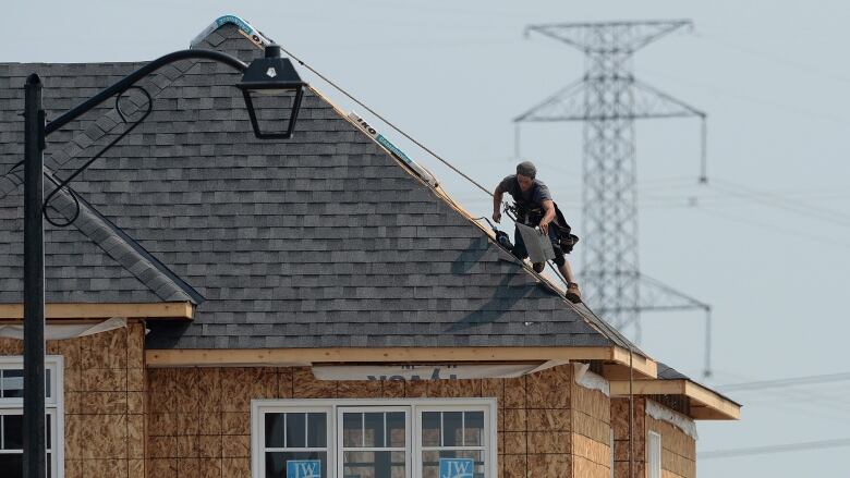 A man puts shingles on a roof.