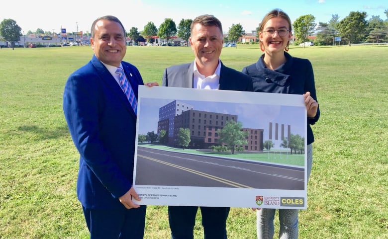 Three people hold an oversized architect's drawing of a new building.