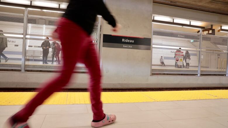 A photo of a woman walking through the Rideau station on Ottawa's light rail line the day the line opened to the public in 2019.