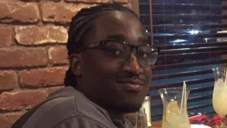 A photo of a young man with glasses sitting at a table at a restaurant.