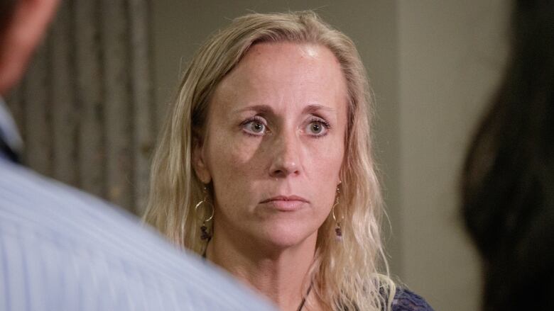 A woman stands outside a courtroom.