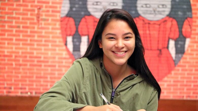 A student sits with a notebook and pen.