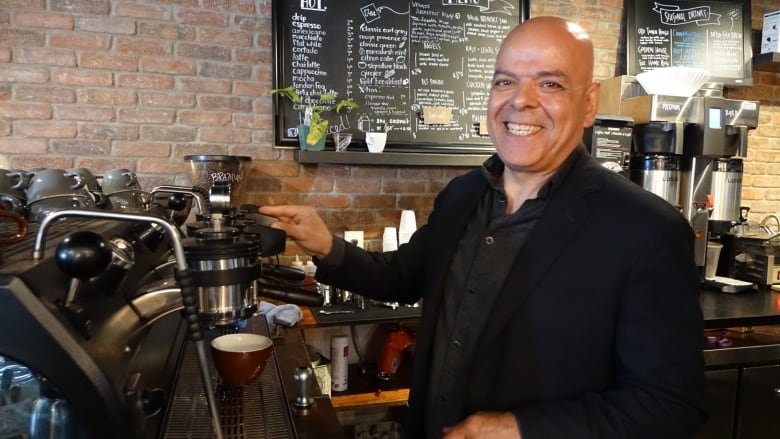 A man stands at a coffee machine in a cafe.