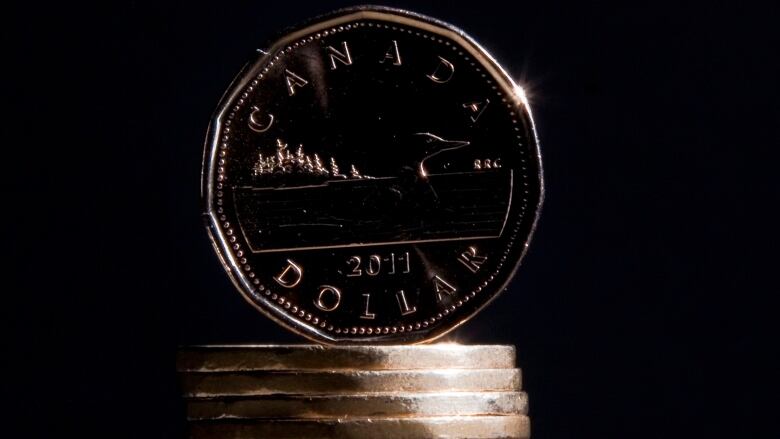 A Canadian loonie sits atop a small pile of coins.