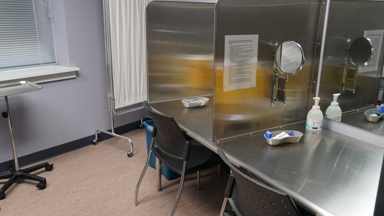 A metal table and plastic chair inside a room with metel dividers to give people privacy.