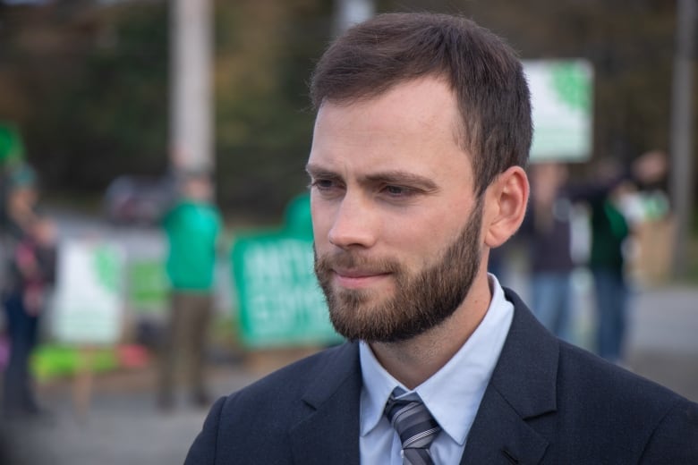 man stands in front of green signs