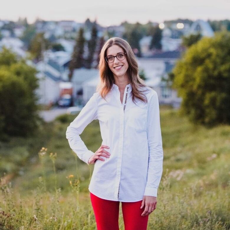 A woman with glasses standing in a field.