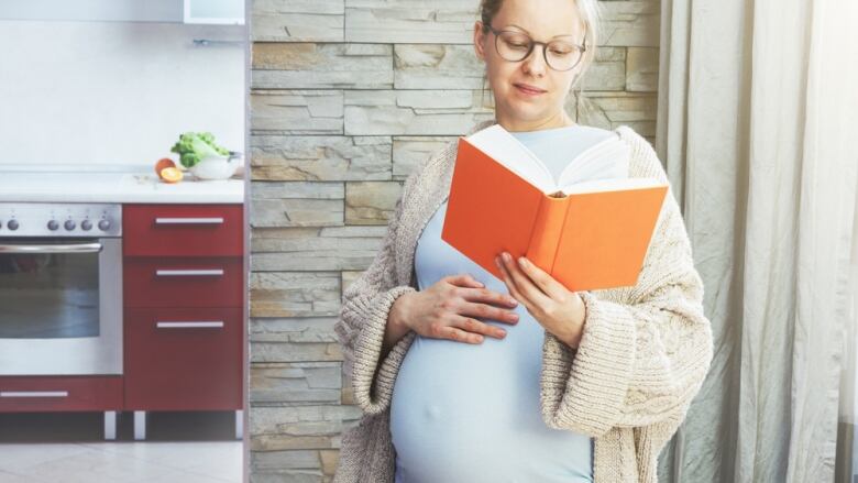 A pregnant woman reads a book.