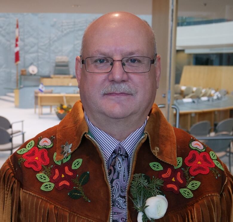 A portrait of a man in a beaded moose leather jacket.