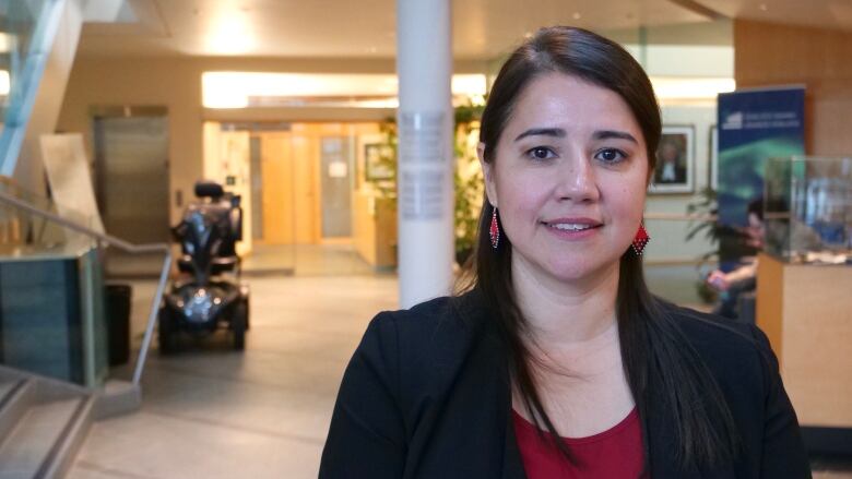 A woman stands in the foyer of an institutional building.