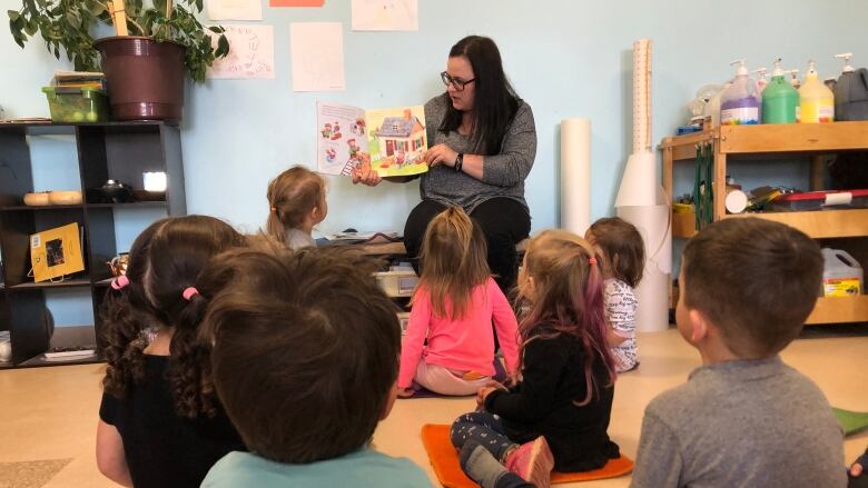 A woman reading a book to young children.