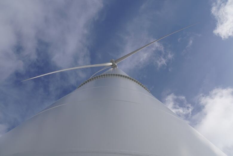 A wind turbine is seen from the ground.