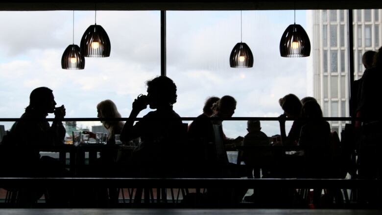 The silhouettes of diners at a restaurant are pictured.