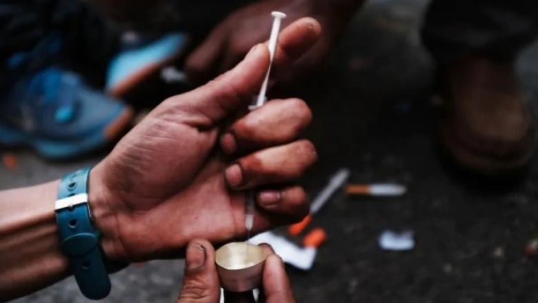 A hand holding a needle and syringe is about to do drugs. 