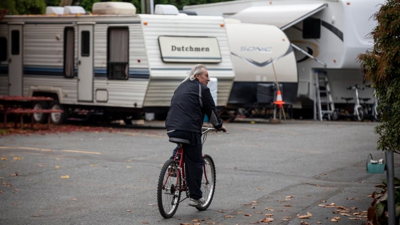 A man bikes through an RV park.