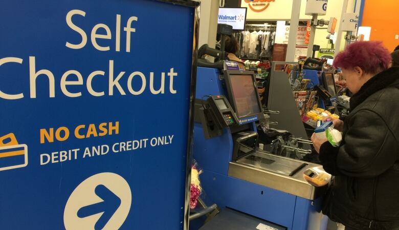 A self-checkout machine and sign at Walmart.