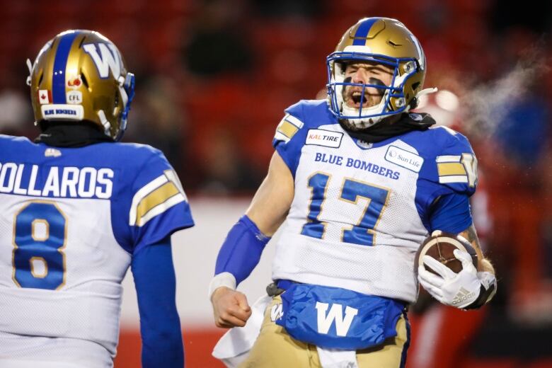 Two football players celebrate on a cold day, their breath seen outside their facemasks.