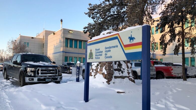 A building and a sign out front, covered in snow. Truck in parking lot also visible.