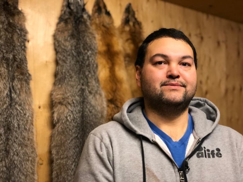 A portrait of a man in front of a wall of pelts.