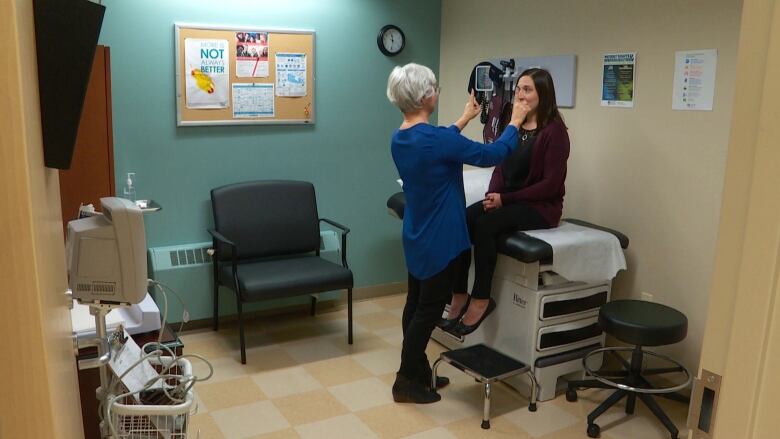 Woman uses a medical instrument to check the eyesight of a patient. 