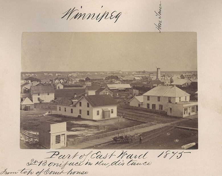 Black and white photo of mud streets and a few buildings