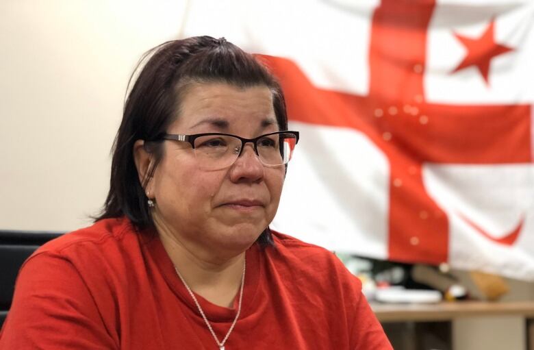 An Indigenous woman poses with a backdrop of the Mi'kmaw grand council flag behind it