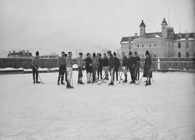 Black and white photo of people skating on hockey rink