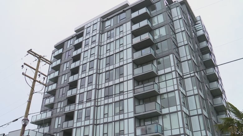 A tall, modern-looking glass-clad apartment building is pictured.