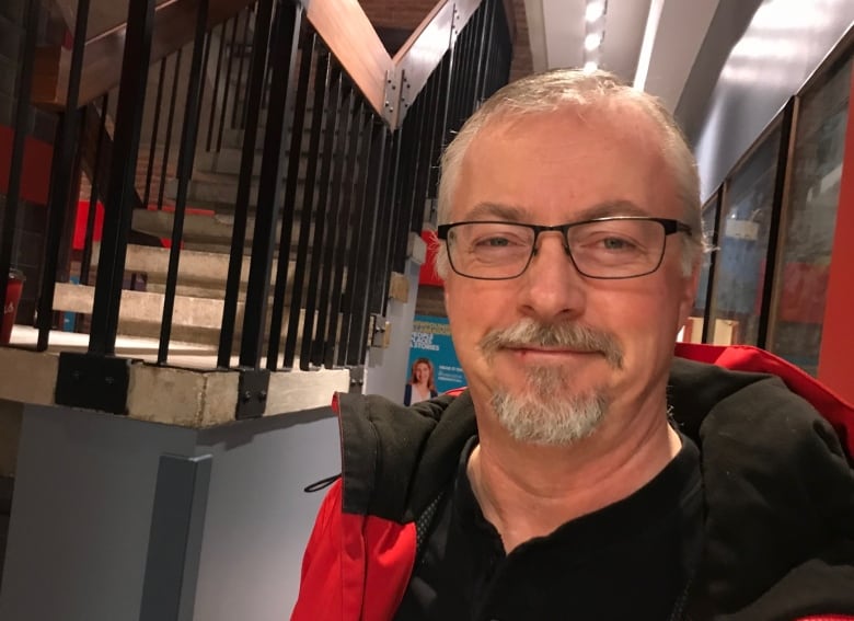 A smiling man wearing a red jacket.