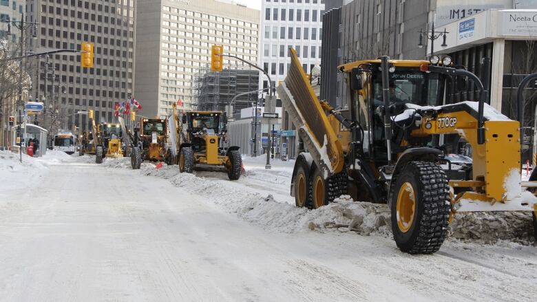 Several snow plows can be seen clearing a street. 