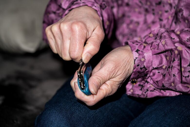 An elderly woman opens a coin purse.