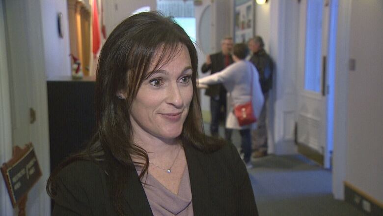 A dark haired woman stands in the corridor of P.E.I.'s legislature during an interview.