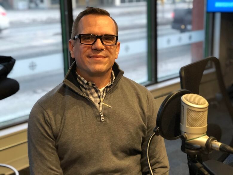 Mark Fraser sits in front of a microphone at the CBC Sudbury studios. 