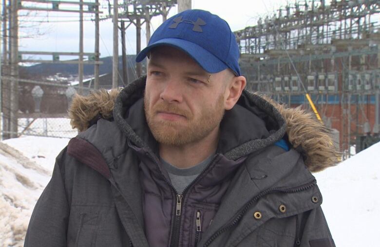 Sherwin Flight stands in front of a snowbank. He's wearing a blue baseball hat and a black winter coat.